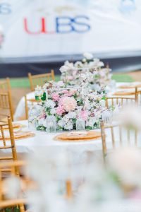 Elegant centerpiece with full floral arrangement with white, peach, pink glass base, charger plates, menu card, glass cups