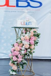 gold cake stand with mirror, green, white, peach and pink floral arrangement with rectangular cake on top