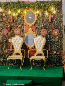 Traditional Wedding, eru iyawo set up for traditional engagement, yam n rack, boxes, baskets, palm oil, gift items for yoruba traditional wedding, parents sofa and couple chairs with green backdrop stage and mirrors with astroturf