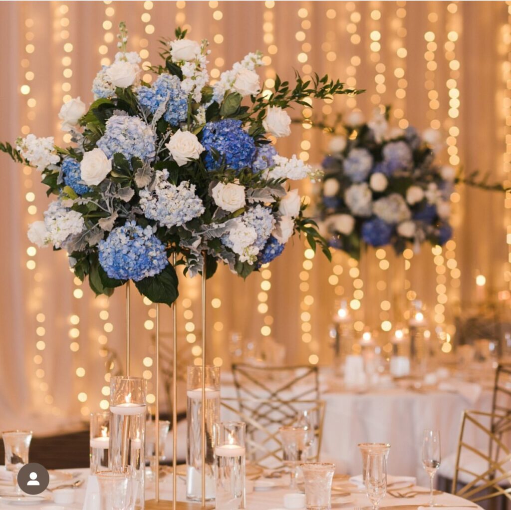 gold centerpiece stand with lavender, blue, green floral arrangement, event decoration, table arrangement, candles