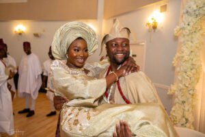 Nigerian couple in Canada traditional wedding, white agbada, champagne gold silk aso oke, walking stick, fila, coral and ivory bead iyun, groom carrying his bride/wife, yoruba culture, traditional wedding