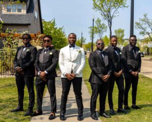 Debola and Okiki white wedding in Canada, white wedding dress gown, white suit on groom with black pant, buttonnaire, white floral bouquet with memorabilia picture of mum, elegant smile, bridal make up, wrist watch, groom and his groomsmen photoshoot, outdoor wedding