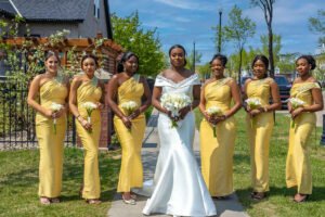 Debola and Okiki white wedding in Canada, white wedding dress gown, white suit on groom with black pant, buttonnaire, white floral bouquet with memorabilia picture of mum, elegant smile, bridal make up, wrist watch, bride and her girls, bridesmaids yellow brown gown dress