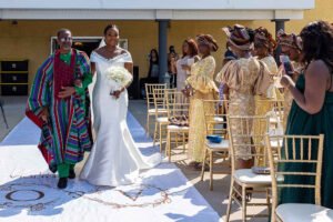 Debola and Okiki white wedding in Canada, white wedding dress gown, white suit on groom with black pant, buttonnaire, white floral bouquet with memorabilia picture of mum, elegant smile, bridal make up, wrist watch, beaded after party bridal dress, couple look, walking down the aisle song with father, Dad,