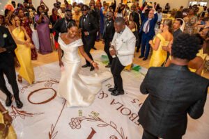 Debola and Okiki white wedding in Canada, white wedding dress gown, white suit on groom with black pant, buttonnaire, white floral bouquet with memorabilia picture of mum, elegant smile, bridal make up, nigerian wedding reception in canada, dancefloor, couple first dance