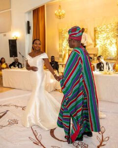 Debola and Okiki white wedding in Canada, white wedding dress gown, white suit on groom with black pant, buttonnaire, white floral bouquet with memorabilia picture of mum, elegant smile, bridal make up, wrist watch, father daughter dance, indoor wedding