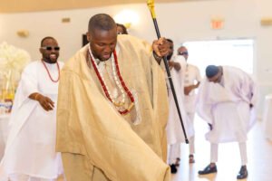Nigerian couple in Canada traditional wedding, white agbada, champagne gold silk aso oke, walking stick, fila, coral and ivory bead iyun, groom dancing with friends
