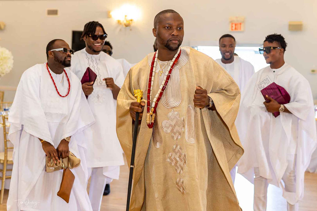 Nigerian couple in Canada traditional wedding, white agbada, champagne gold silk aso oke, walking stick, fila, coral and ivory bead iyun, groom dancing with friends