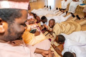 Nigerian couple in Canada traditional wedding, white agbada, champagne gold silk aso oke, walking stick, fila, coral and ivory bead iyun, groom dancing with friends, Yoruba culture prostrating during engagement