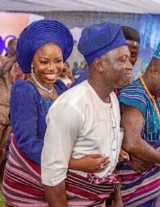 Nigerian couple yoruba traditional wedding photoshoot, blue agbada, aso oke, gele, attire and outfit. Yoruba fila, rich ondo state culture for traditional wedding. Couple backed by parent - bride