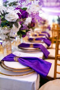 purple and white birthday design for 80th year old grandma with chiavari chairs, green astroturf, flowers, purple table scape, table setting, gold rim plates, purple floral arrangement on tables