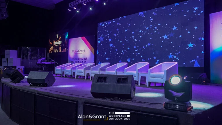 Eventigo The workplace outlook conference stage design with LED screen stage props banners lounges white couch side stools event planner in Lagos full view of stage design 768x432 1